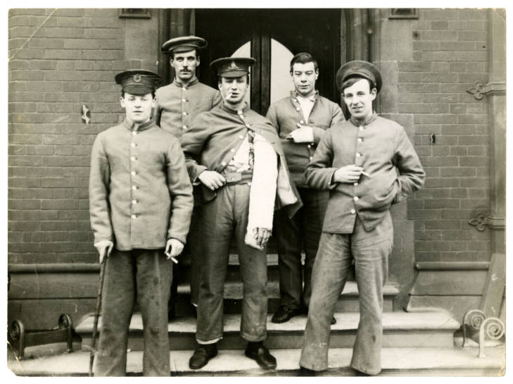 Photograph of wounded servicemen standing outside the steps of the Armstrong Building 